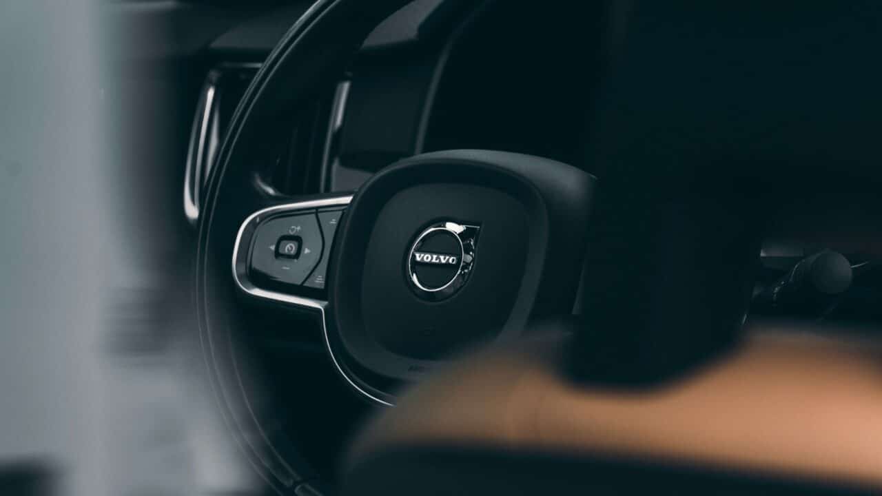 Volante de um carro Volvo visto em close-up, com acabamento em couro preto e o logotipo circular da Volvo em cromado ao centro
