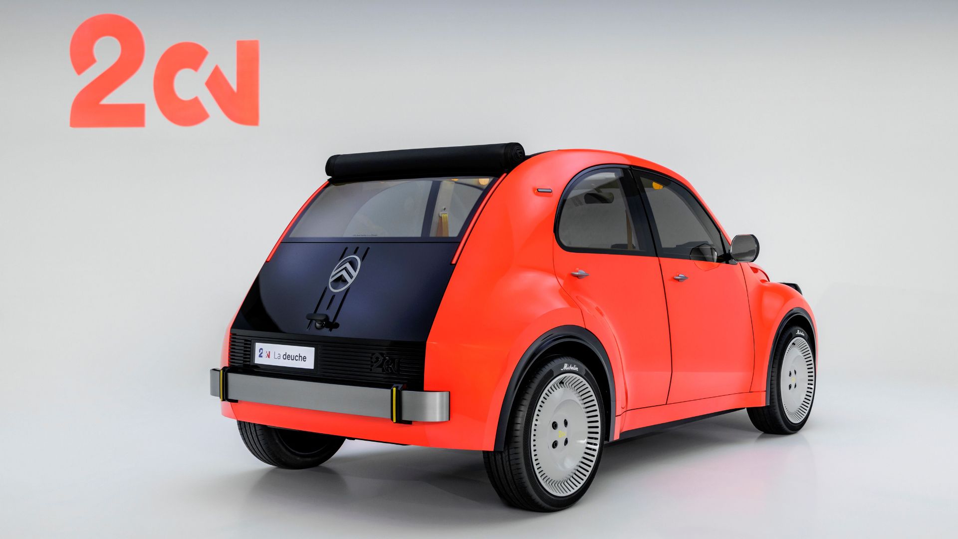 Vista traseira três-quartos do Citroën 2CV Concept elétrico laranja. A traseira exibe uma janela traseira escura, o logotipo da Citroën, uma placa de identificação "La deuche" e um para-choque prateado com detalhes em amarelo. O teto de tecido enrolado é visível no topo
