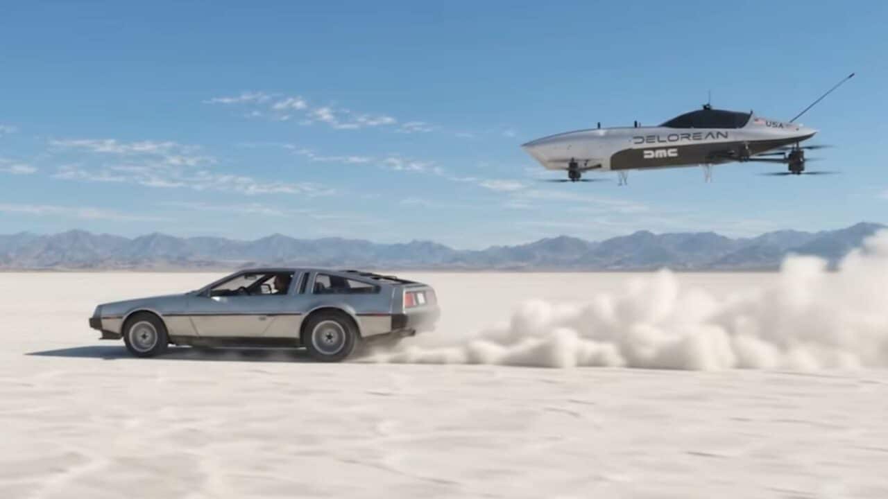 Um DeLorean clássico prateado dirigindo em alta velocidade em um deserto de sal, levantando uma nuvem de poeira, enquanto um veículo voador elétrico da DeLorean (com a inscrição 'DELOREAN DMC' e uma bandeira dos EUA) flutua acima dele no céu azul, com montanhas ao fundo.