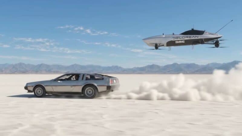 Um DeLorean clássico prateado dirigindo em alta velocidade em um deserto de sal, levantando uma nuvem de poeira, enquanto um veículo voador elétrico da DeLorean (com a inscrição 'DELOREAN DMC' e uma bandeira dos EUA) flutua acima dele no céu azul, com montanhas ao fundo.