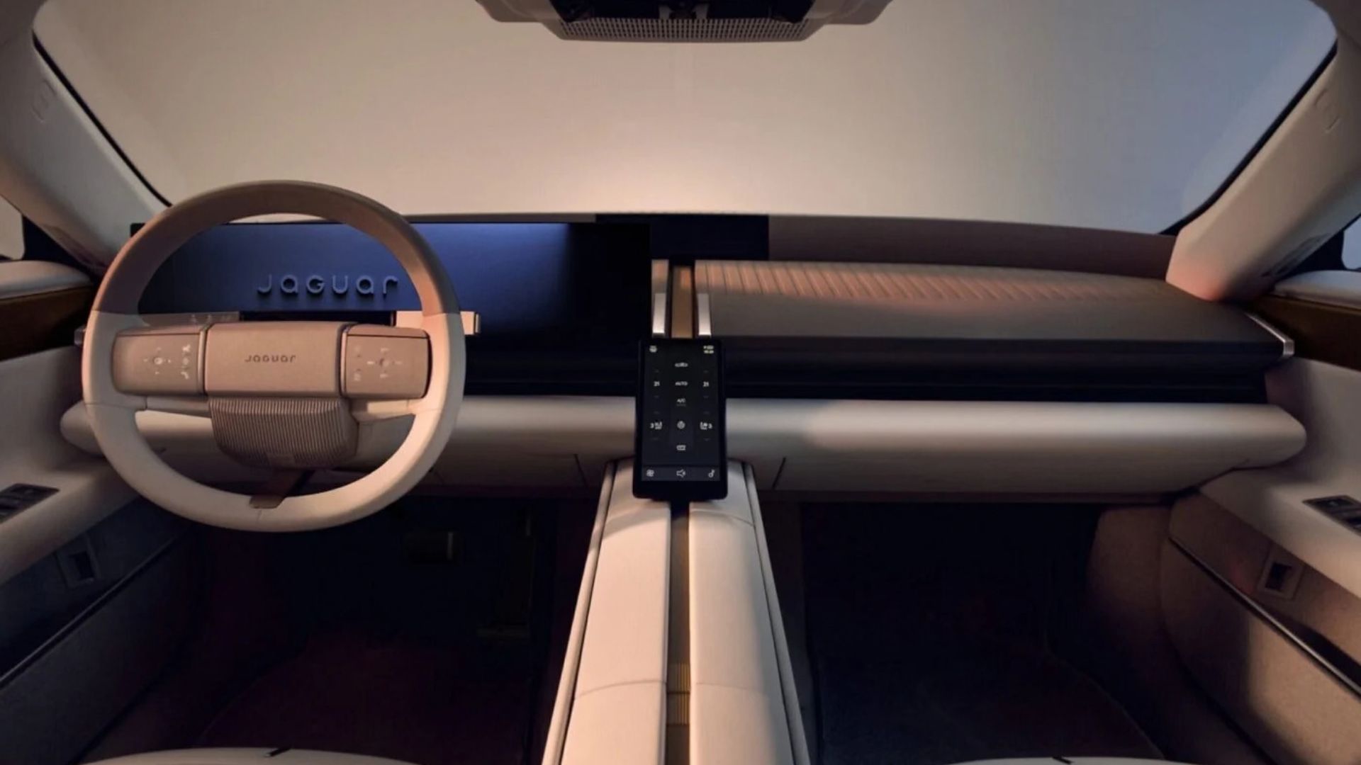 Interior minimalista do Jaguar Type 01, mostrando o volante de dois raios com o logotipo Jaguar, uma tela digital de 24 polegadas atrás do volante e uma pequena tela vertical de 7 polegadas no console central entre os assentos