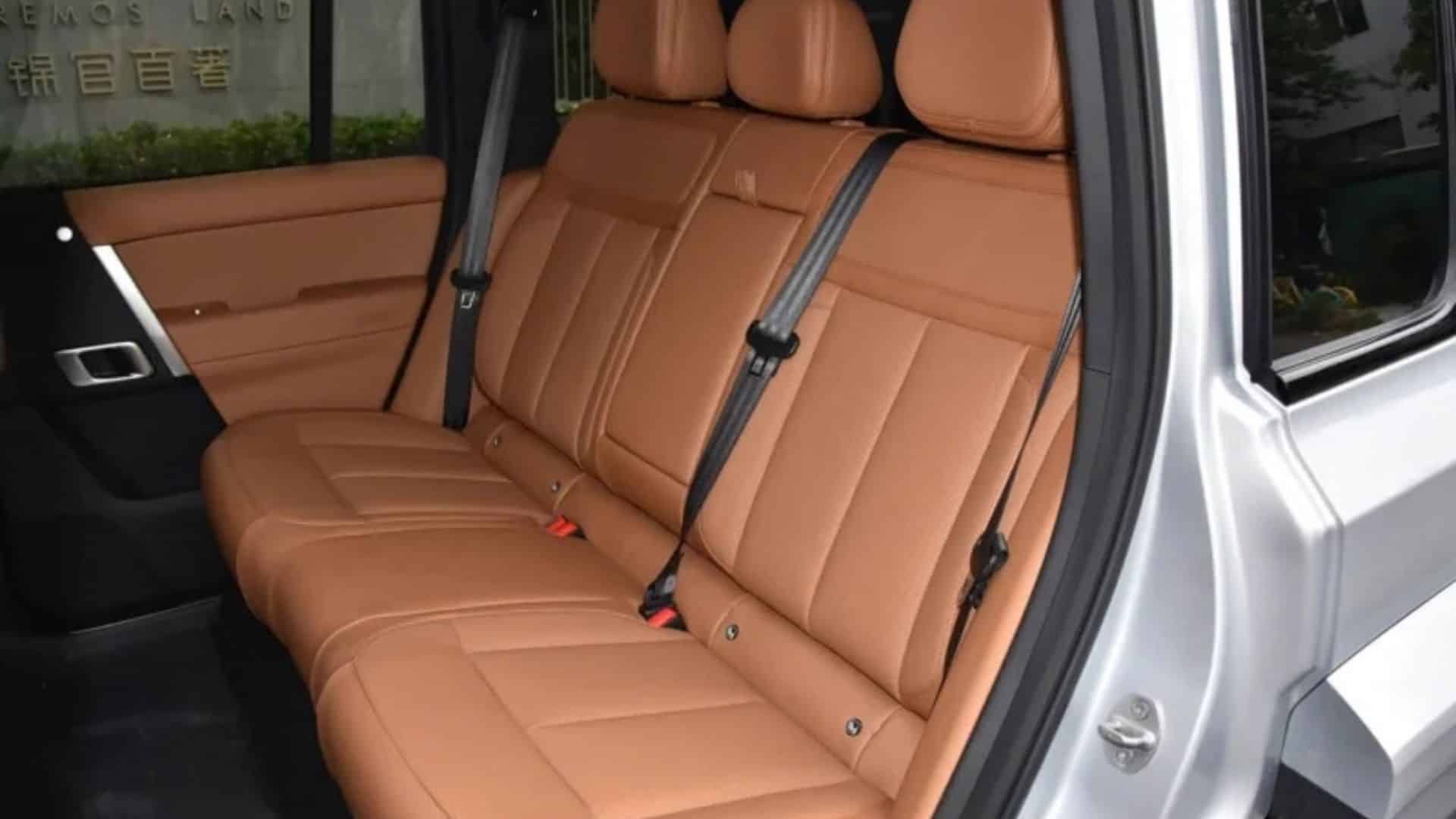 Interior do iCar V27 com bancos traseiros de couro marrom-claro, cintos de segurança e detalhes em preto, vistos através da porta aberta