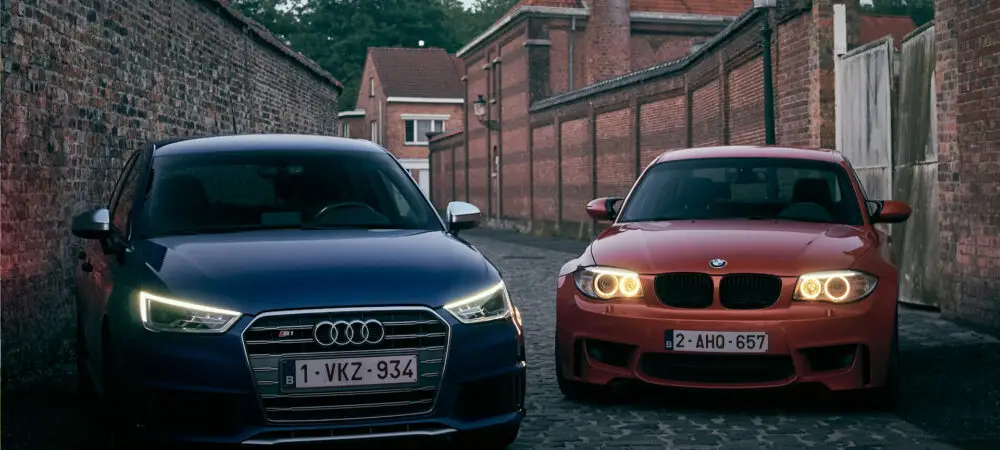Dois carros, um Audi S1, e um BMW 1M, parados lado a lado