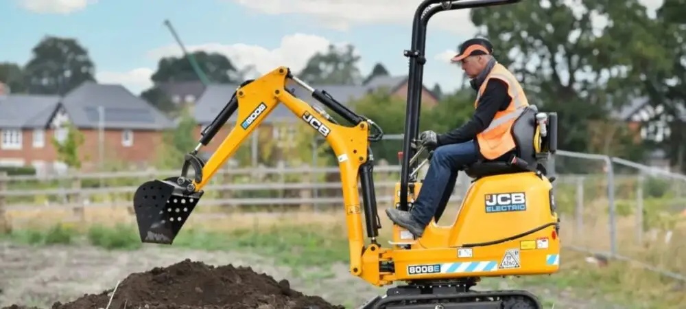 Empresário britânico Colin Ash dirigindo escavadeira elétrica num campo na Inglaterra
